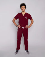 Junger Arzt mit moderner dunkelroter medizinischer Arbeitskleidung und weißen Sneakern