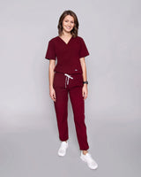 Junge Ärztin in Sneakern und moderner medizinischer Damenhose in dunkelrot