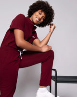 Junge Ärztin in medizinischer Berufsbekleidung in dunkelrot lächelt in die Kamera