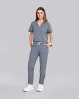 Junge Ärztin in Sneakern und moderner medizinischer Damenhose in grau