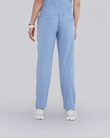 Junge Ärztin in Sneakern und moderner medizinischer Damenhose in hellblau