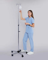 Junge Medizinerin in medizinischer Berufsbekleidung in hellblau lächelt in die Kamera