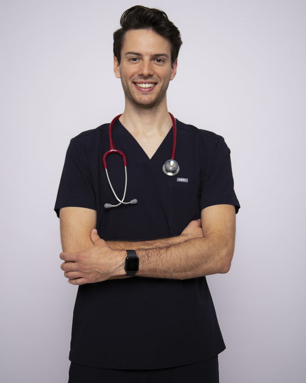Junger Arzt mit rotem Stethoskop, Apple Watch und modernem Kasack in dunkelblau