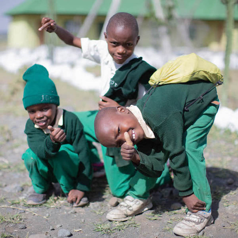 3 glückliche Schulkinder in Afrika in ihrer grünen Schuluniform