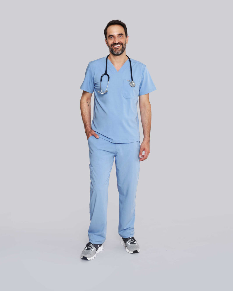 Junger Arzt in Sneakern mit Apple Watch und moderner Praxiskleidung in hellblau