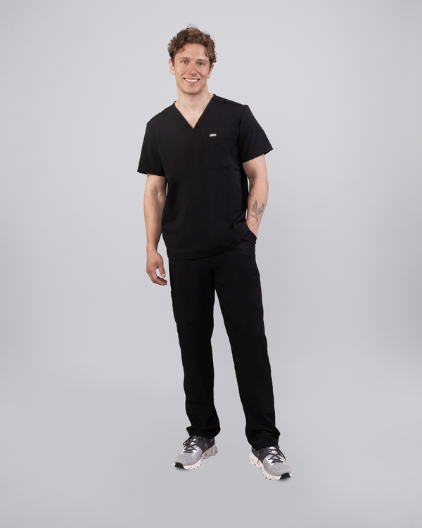 Junger Arzt in Sneakern mit Apple Watch und moderner Praxiskleidung in schwarz