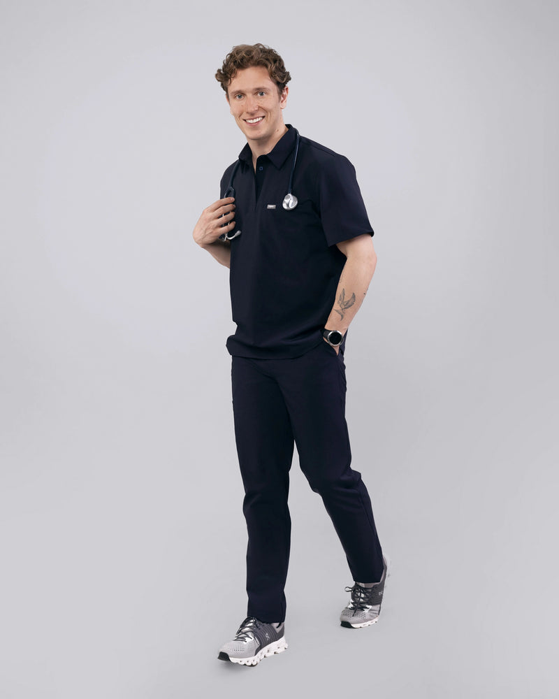 Junger Arzt mit dunkelblauem medizinischem Poloshirt und elegantem Kragen
