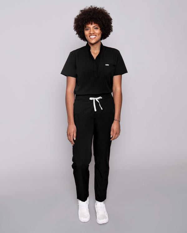 Junge Ärztin in bequemer medizinischer Arbeitskleidung in schwarz