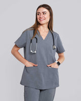 Junge Medizinerin in medizinischer Berufsbekleidung in grau lächelt in die Kamera