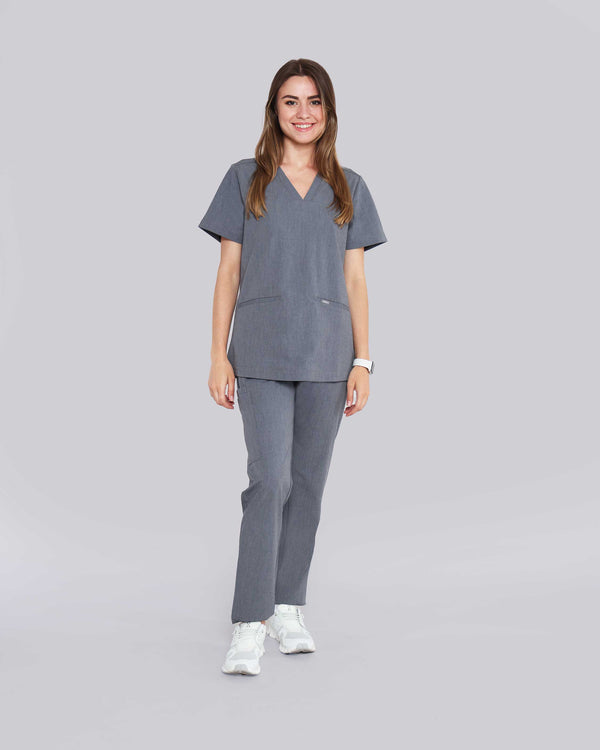 Junge Medizinerin in weißen Sneakern und moderner Arbeitsbekleidung in grau