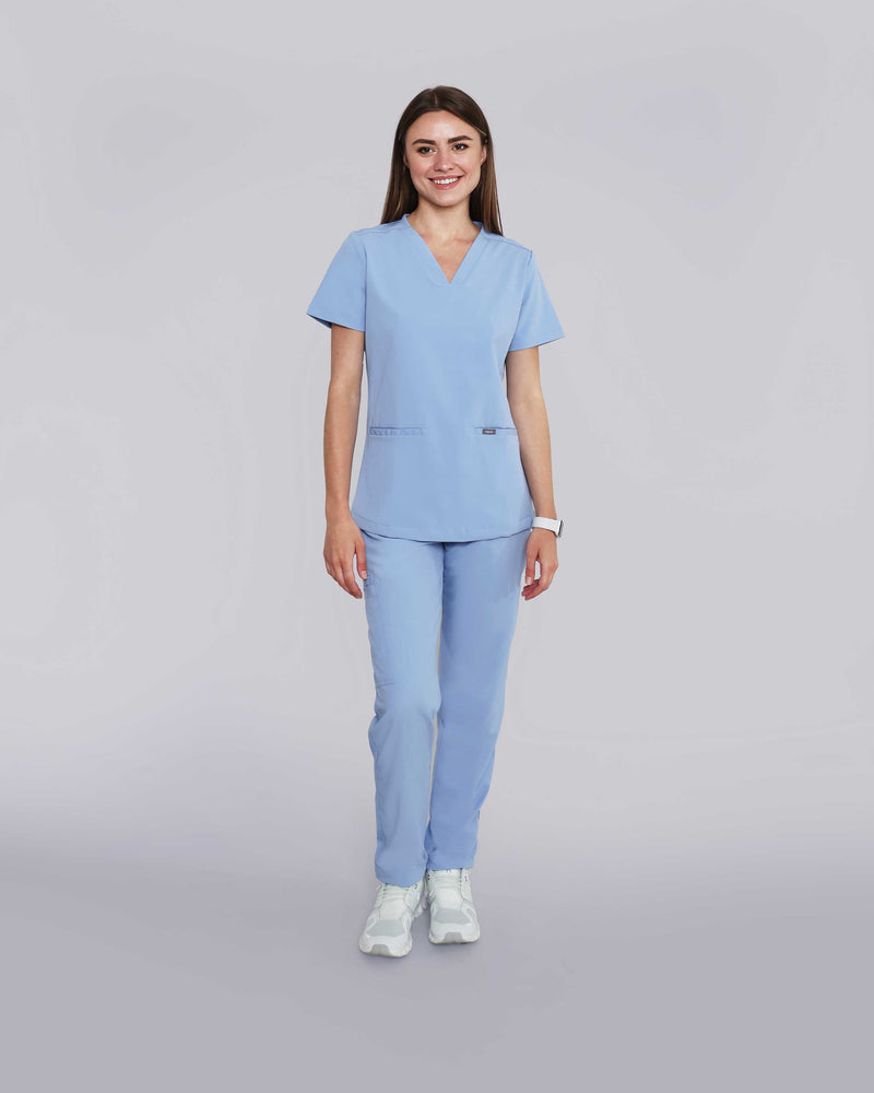 Junge Medizinerin in weißen Sneakern und moderner Arbeitsbekleidung in hellblau