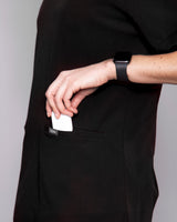 unge Medizinerin mit moderner medizinischer Arbeitskleidung in schwarz mit praktischen Fronttaschen