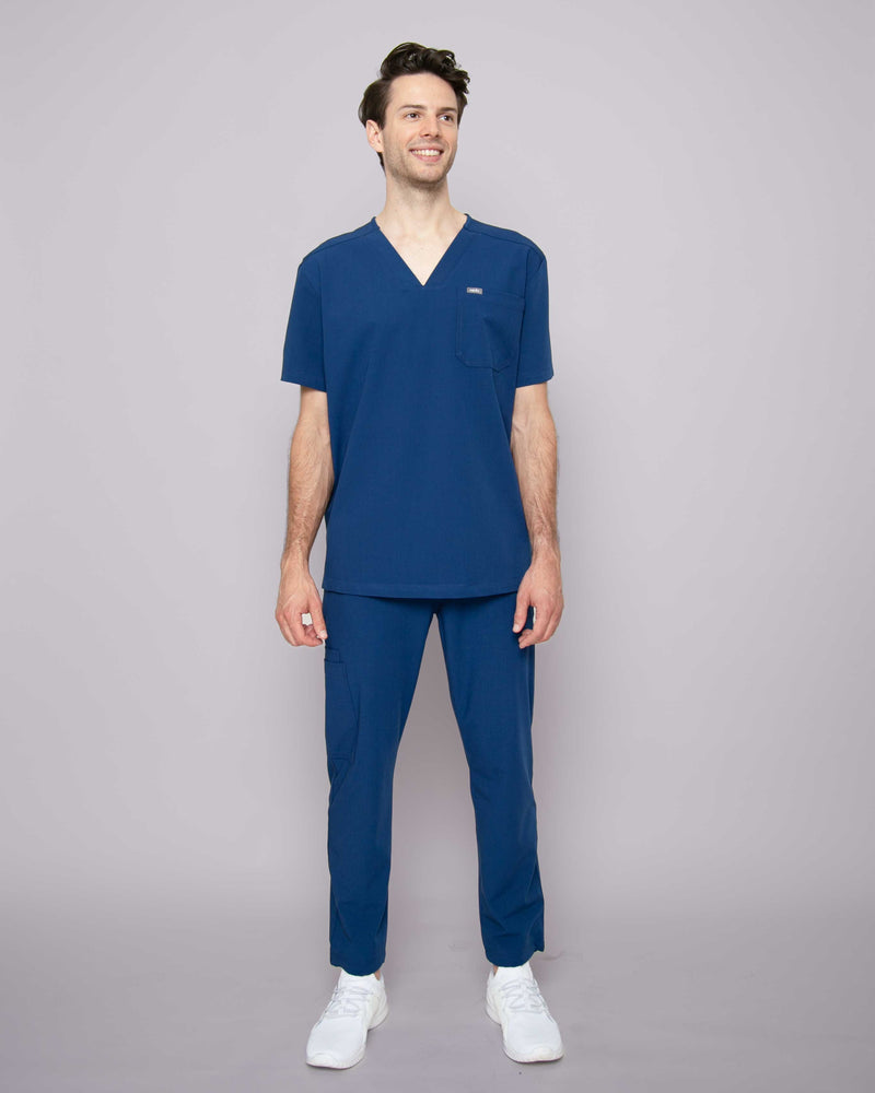 Junger Arzt mit moderner blauer medizinischer Arbeitskleidung und weißen Sneakern