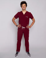 Junger Arzt mit moderner dunkelroter medizinischer Arbeitskleidung und weißen Sneakern