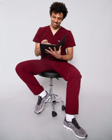 Junger Arzt mit Stethoskop und moderner medizinischer Berufsbekleidung in dunkelrot