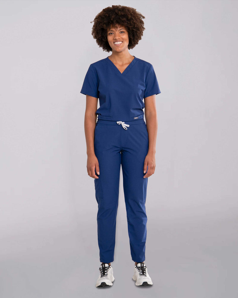 Junge Ärztin in Sneakern und moderner medizinischer Damenhose in blau