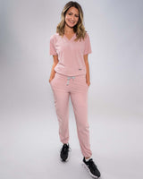 Junge Ärztin in schwarzen Sneakern und moderner Arbeitsbekleidung in rosa