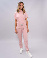 Junge Ärztin in Sneakern und moderner medizinischer Damenhose in rosa