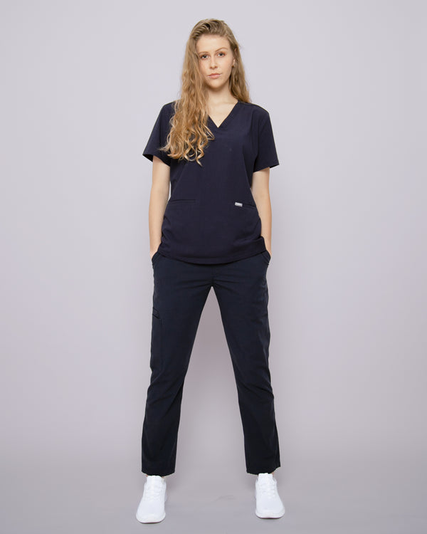 Junge Ärztin in weißen Sneakern und moderner Arbeitskleidung in dunkelblau